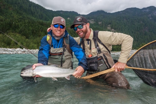 happy fly fishing guide and client with a bull trout